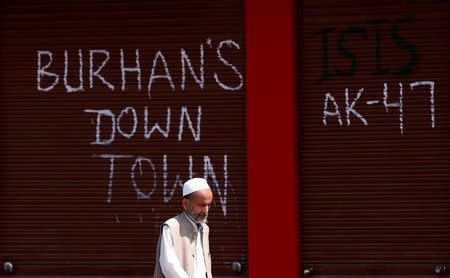 A man walks past closed shops painted with graffiti during a curfew in Srinagar, July 24, 2016. REUTERS/Danish Ismail