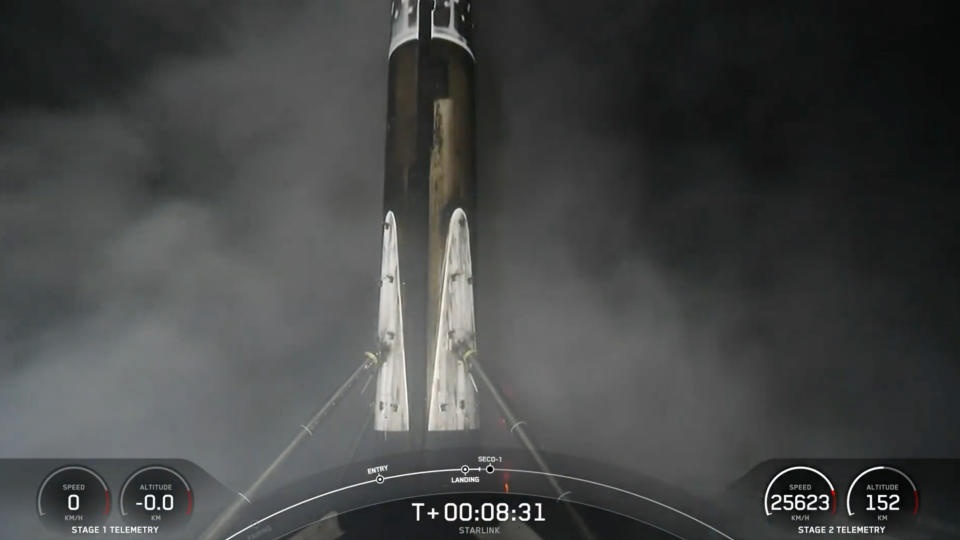 a black and white rocket rests on the deck of a ship at night.