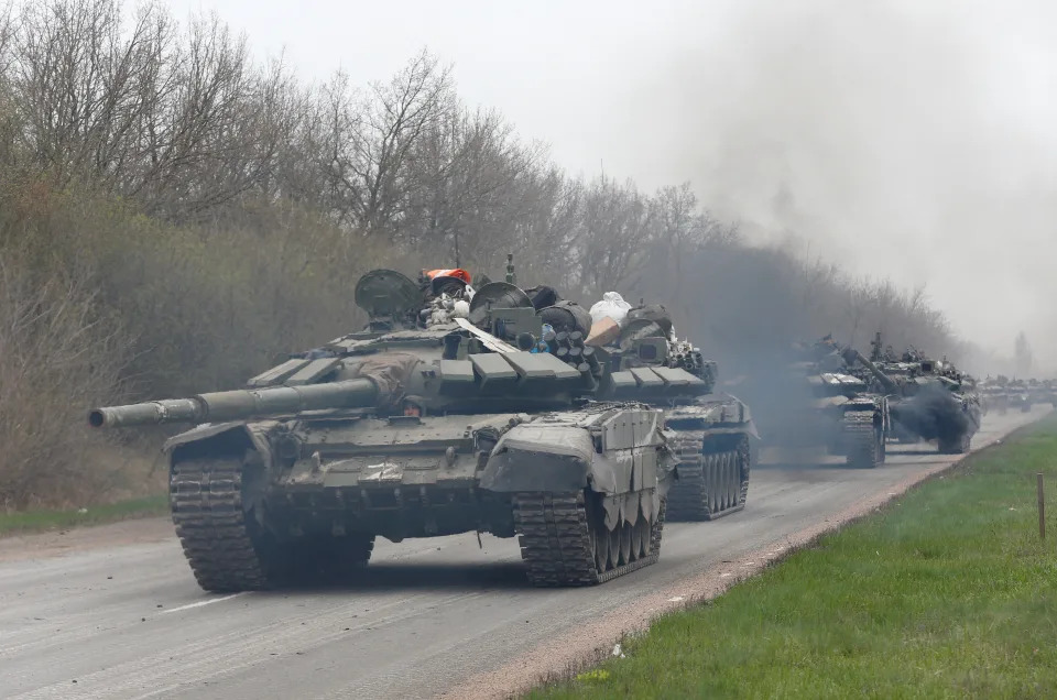 Several tanks travel along a road.