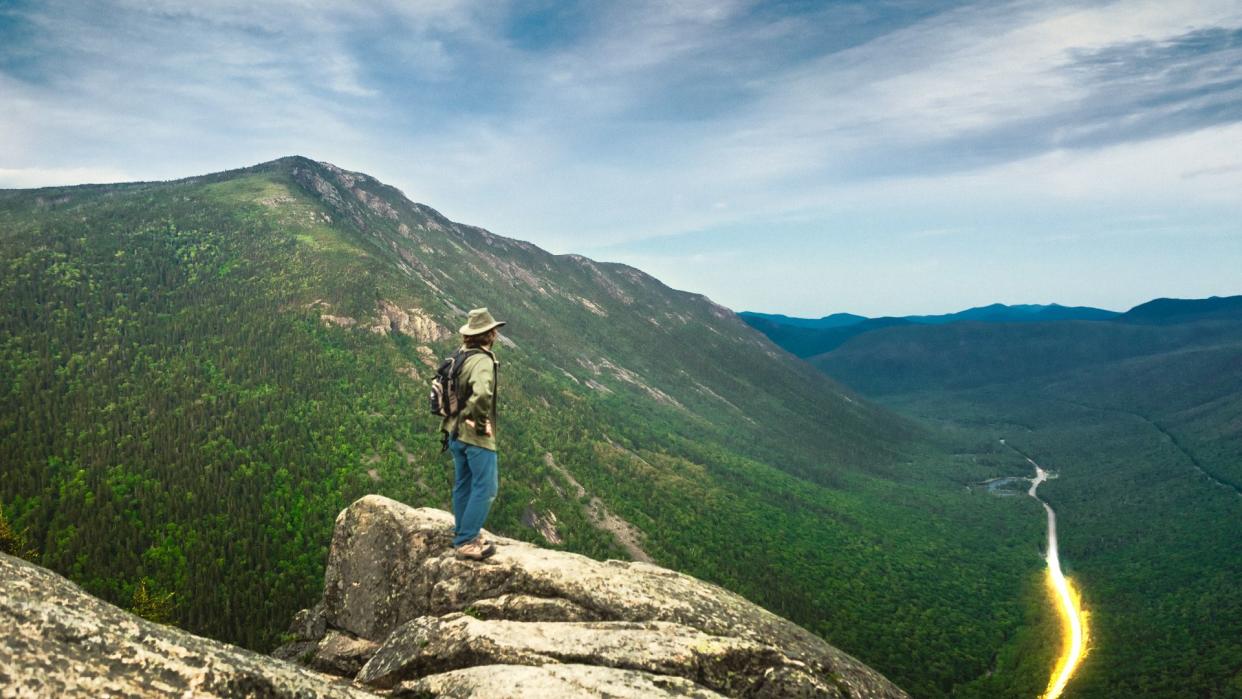 Male hiker standing on the cliff of Mt Willard overlooking Crawford Notch in New Hampshire on the calm spring evening.