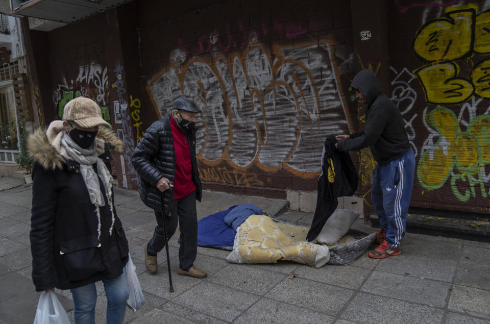 Juan Gana, de 45 años, recoge sus pertenencias luego de despertarse tras pasar la noche en una calle de Buenos Aires, Argentina, el lunes 8 de agosto de 2022. Juan, quien durante cuatro años trabajó como zapatero, vive en la calle, donde sobrevive cuidando automóviles. (AP Foto/Rodrigo Abd)