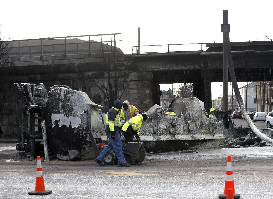 Crews clean up the site where a tanker overturned and burst into flames early in the morning near train tracks on Route 21 in Newark, N.J., Thursday, March 13, 2014. The tanker burst into flames after colliding with a car on McCarter Highway adjacent to Amtrak's Northeast Corridor rail line in Newark at about 1:45 a.m. Thursday. That caused problems for Amtrak's signals and overhead wires. Amtrak service is running with minor delays. (AP Photo/Julio Cortez)