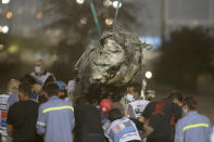 A part of Haas driver Romain Grosjean's car is taken after the crash at the start of the Formula One Bahrain Grand Prix in Sakhir, Bahrain, Sunday, Nov. 29, 2020. (Tolga Bozoglu, Pool via AP)