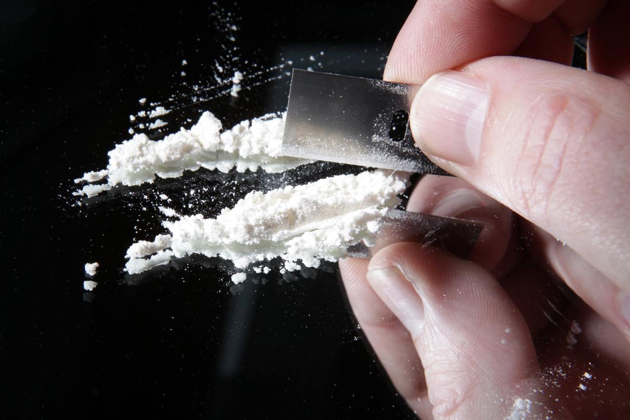 hand cutting cocaine with blade