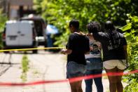 People watch as officials remove four bodies from a house on South Morgan Street in Chicago's South Side on Tuesday, June 15, 2021.