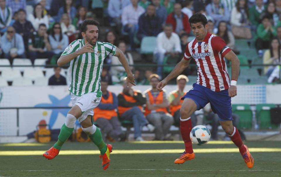 Atletico de Madrid's Diego Costa, right, and Betis' Jordi Figueras , left, vie for the ball during their La Liga soccer match at the Benito Villamarin stadium, in Seville, Spain on Sunday, March 23, 2014. (AP Photo/Angel Fernandez)