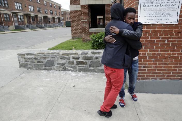 Ronte Jenkins, right, a lifelong friend of Freddie Gray, hugs a friend at the site of Gray&#39;s arrest, back left, Friday, May 1, 2015, in Baltimore, after the announcement of charges against the police officers involved in Gray&#39;s arrest. (AP Photo/Patrick Semansky)