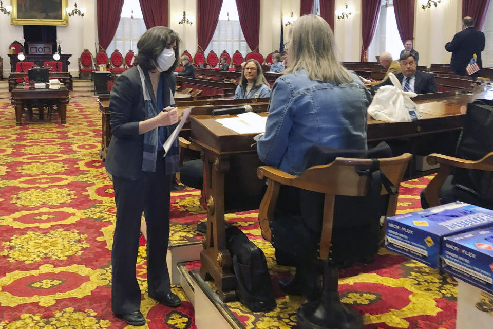 FILE - In this March 25, 2020 file photo, Vermont House Speaker Mitzi Johnson, left, wears a mask while talking to a lawmaker in the Vermont house chamber at the Statehouse in Montpelier, Vt. In state capitols across the U.S., lawmakers have ditched decorum and sidestepped traditional public meeting requirements in a rush to pass legislation funding the fight against the coronavirus and aiding residents affected by the widespread shut down of commerce. (AP Photo/Wilson Ring, File)