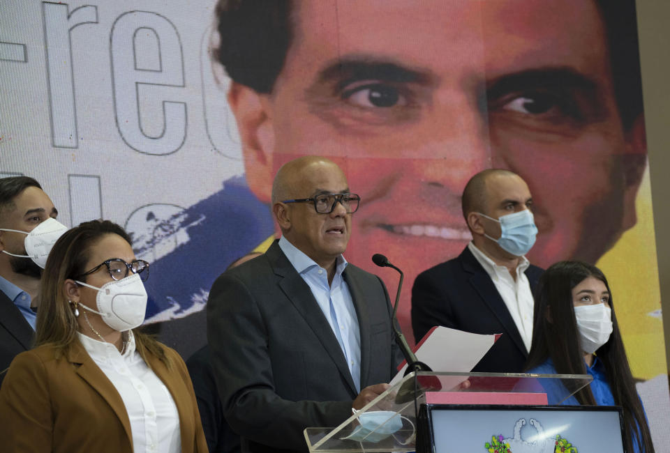 Venezuelan President of the National Assembly Jorge Rodriguez, center, speaks to the press as an image of Colombian businessman and Venezuelan special envoy Alex Saab is in the back in Caracas, Venezuela, Saturday, Oct 16, 2021. Venezuela’s government said Saturday it would halt negotiations with the country's opposition in retaliation for the extradition to the U.S. of a close ally of President Nicolás Maduro wanted on money laundering charges. (AP Photo/Ariana Cubillos)