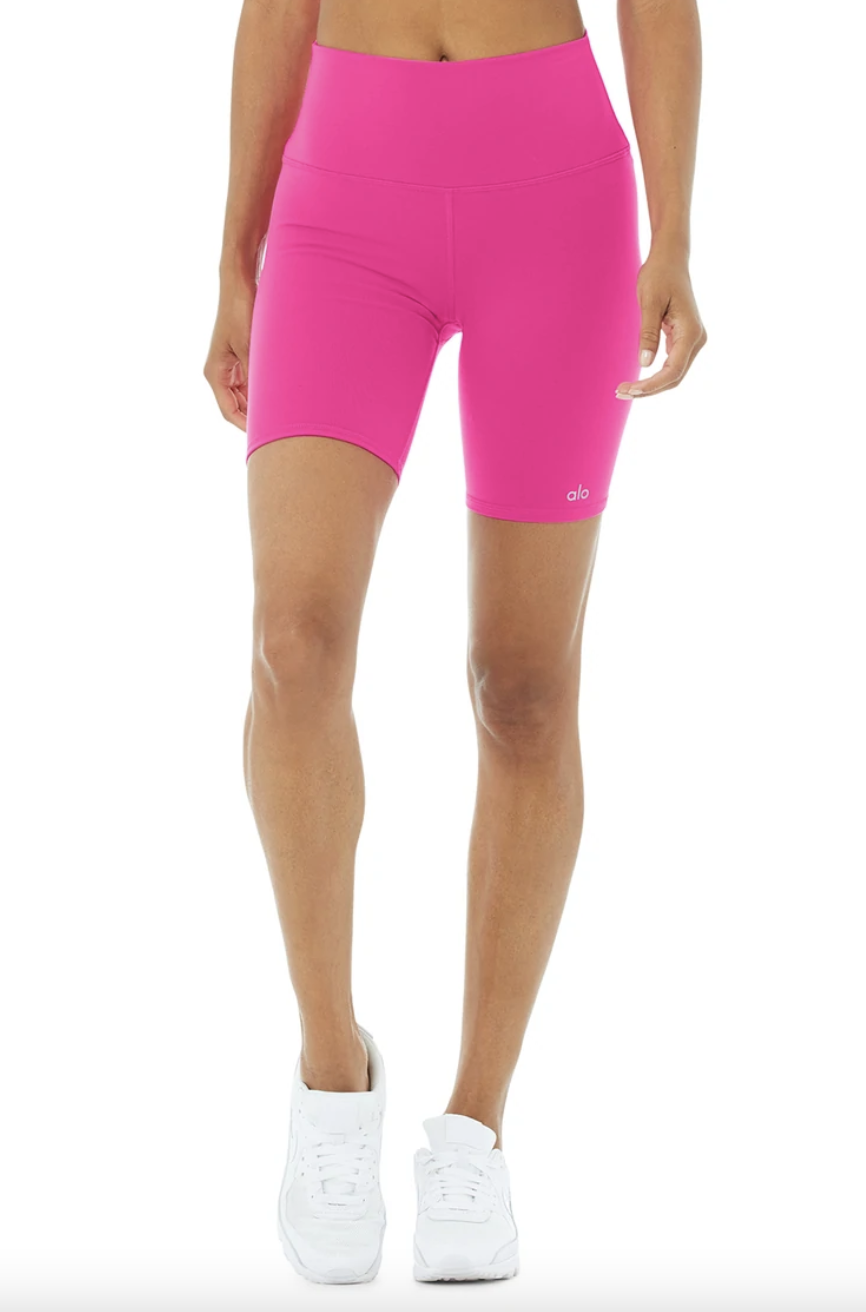 High-Waist Biker Short in hot pink with white sneakers (Photo via Alo Yoga)