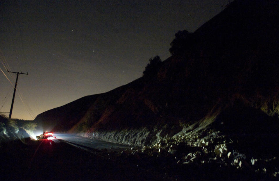 A car sits rolled over near a rockslide, right, in the wake of Friday nights March 28, 2014 earthquake on Carbon Canyon Road in Brea, Calif., near Olinda Village. (AP Photo/The Orange County Register, Rod Veal)