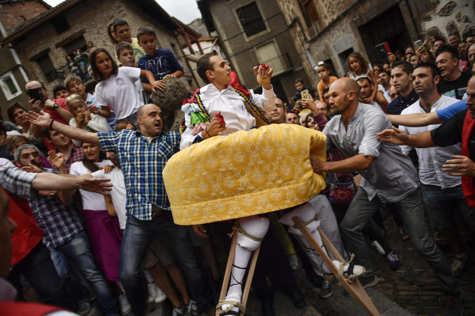 <p>People help a dancer as he performs on stilts in honor of Saint Mary Magdalene in a street for the traditional “Danza de Los Zancos” (Los Zancos Dance), in the small town of Anguiano, northern Spain, July 23, 2016. (AP Photo/Alvaro Barrientos)</p>