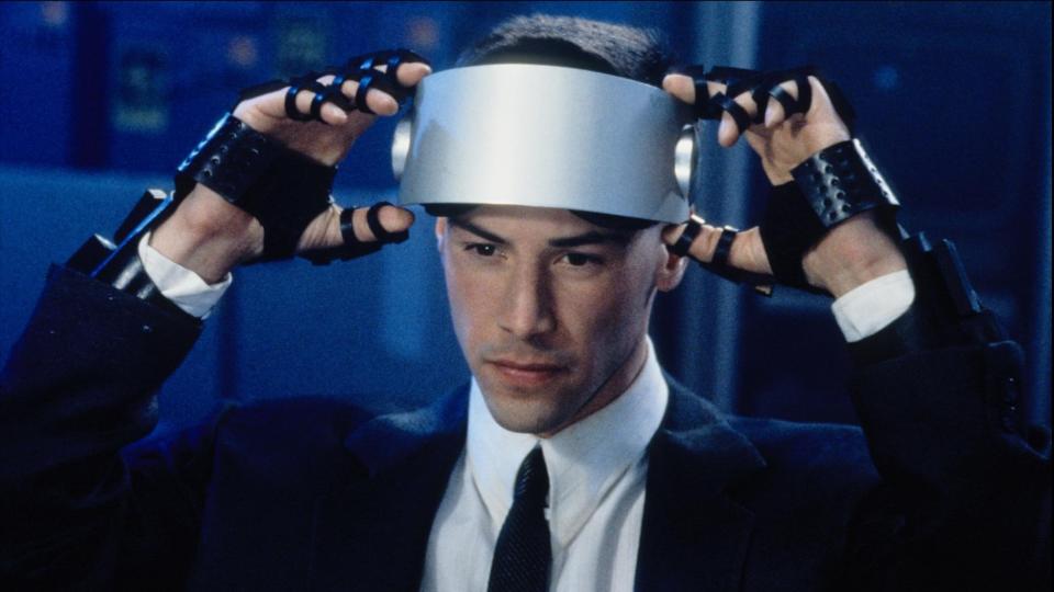  Keanu Reeves about to pull down a VR headset. 