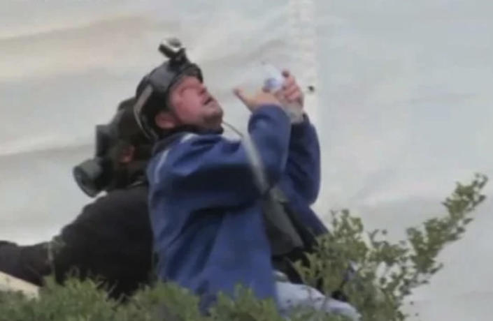 

This still photo from video shows Guy Reffitt, in a blue jacket, rinsing his eyes outside the Capitol on Jan. 6, 2021. (Dept. of Justice)