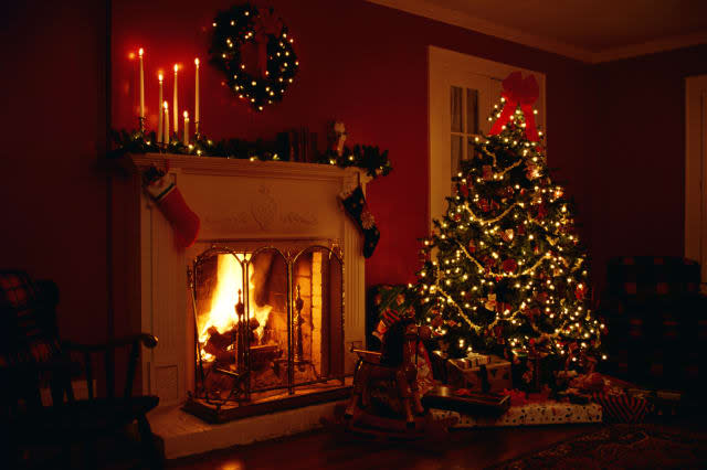 Interior of a lighted Christmas tree near a lit fireplace.