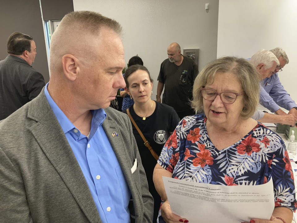 Brian Stransky, of unincorporated Sarpy County, Nebraska, listens as Citizens for Voter ID campaign official Nancy McCabe reads to him from a voter ID ballot petition on Thursday, Sept. 2, 2021, at a local Republican Party meeting in Papillion, Nebraska. Activists who want to require voters to show a government-issued identification at the polls are taking the issue directly to voters after facing years of rejection in the Nebraska Legislature. (AP Photo Grant Schulte)