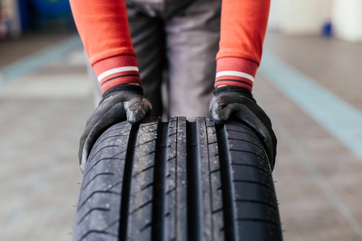 mechanic hands pushing a black tire