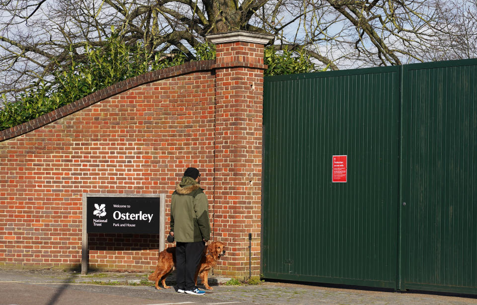 A dog walker looks at the signage the entrance for Osterley Park and House in Isleworth, London, after The National Trust announced it has shut down all of its parks and and gardens across the UK until further notice.