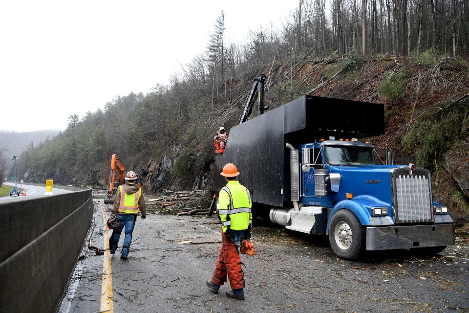 Workers use chainsaws and large machinery to clear I-40 at mile marker 7.5 of debris from a Friday night rockslide on Feb. 23, 2019. The NC Department of Transportation expects the highway to be closed for a week as they clean up and stabilize the area which still had falling trees and rocks Saturday afternoon.