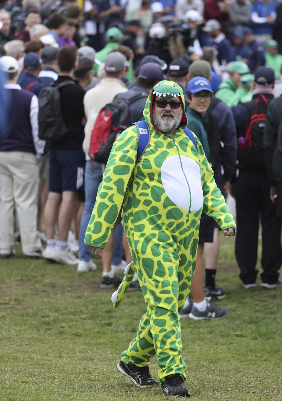 A gold fan dress as a dinosaur joins the crowd watch a practice round for the British Open Golf Championship at Royal St George's golf course Sandwich, England, Wednesday, July 14, 2021. The Open starts Thursday, July, 15. (AP Photo/Ian Walton)