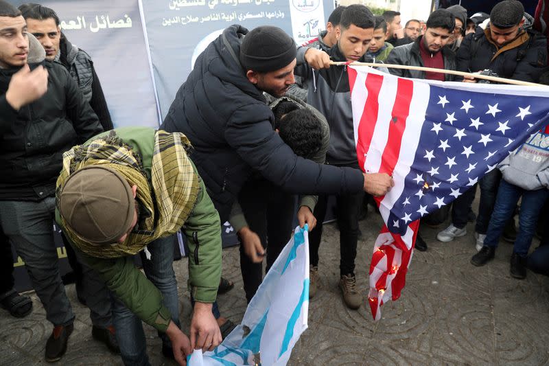 Palestinians burn representations of a U.S. flag and an Israeli flag during a protest against the killing of Iranian Major-General Qassem Soleimani, in Gaza