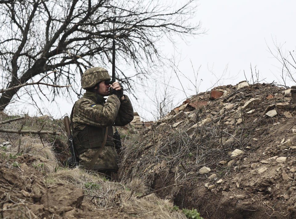 FILE - In this April 12, 2021, file photo, Ukrainian soldier watches through a periscope at fighting positions on the line of separation from pro-Russian rebels near Donetsk, Ukraine. Ukraine and the West have become increasingly worried about the presence of more Russian troops and urged Moscow to pull them back. (AP Photo/File)