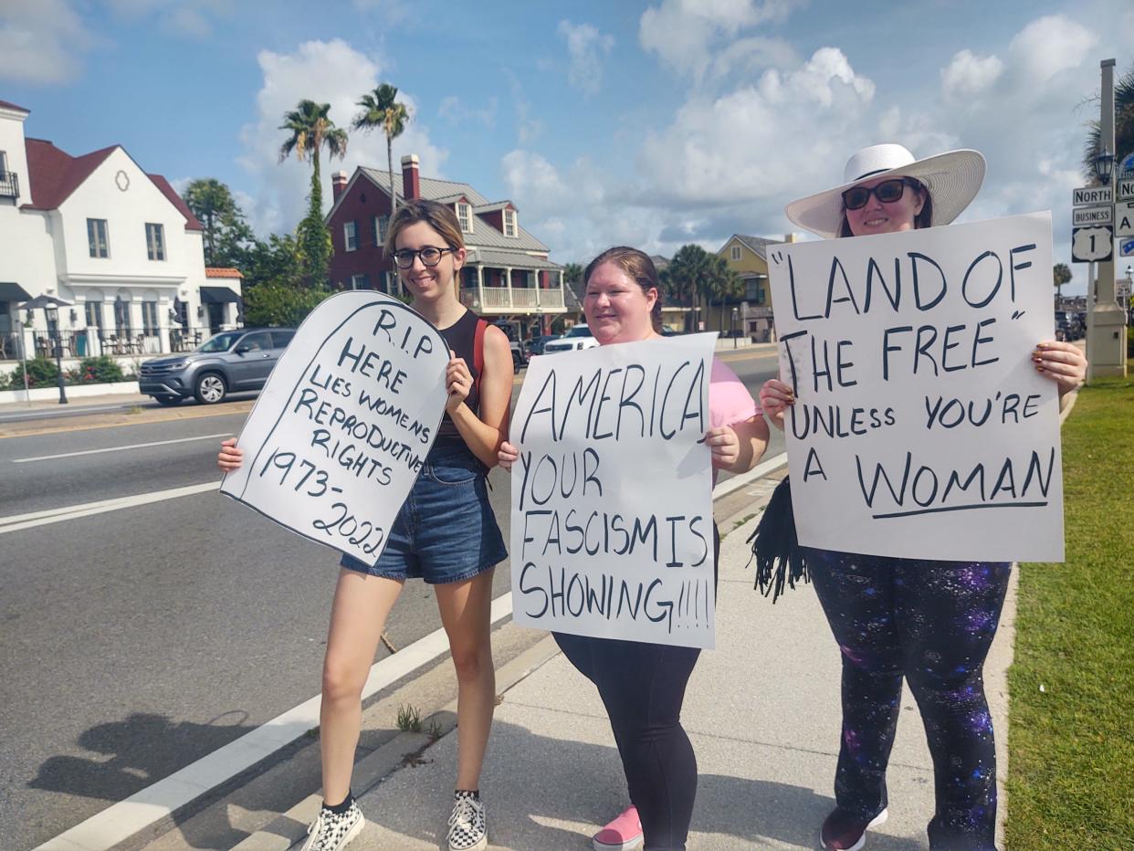 Protestors hold signs near the Bridge of Lions in St. Augustine Saturday, June 25, during a march against the Supreme Court's ruling to overturn Roe v. Wade.