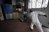 A cemetery worker cremates the remains of a man who died from the new coronavirus, at the crematorium of Zipaquira's Park Cemetery in Zipaquira, Colombia, Friday, June 18, 2021. Funeral workers in Colombia are struggling to dispose of bodies as the country experiences a surge in deaths from COVID-19. (AP Photo/Fernando Vergara)