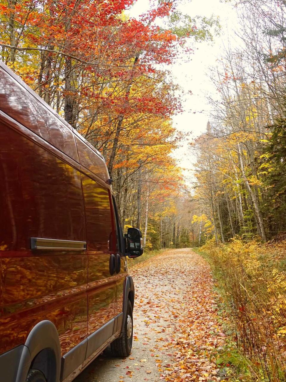 Delury's renovated RV on a road lined in fall foliage