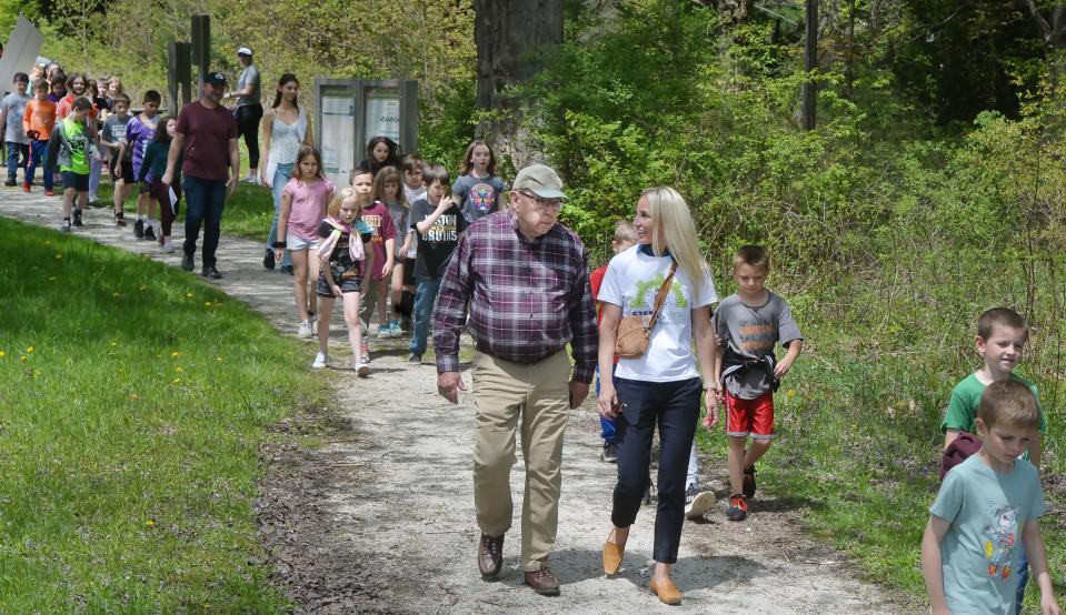 Matt Kerr, center, with the Northwest Pennsylvania chapter of Trout Unlimited, talks with Amy Burniston, who chairs Mercyhurst University's education department, as they lead Earle C. Davis Primary School second-graders toward Lake Pleasant.