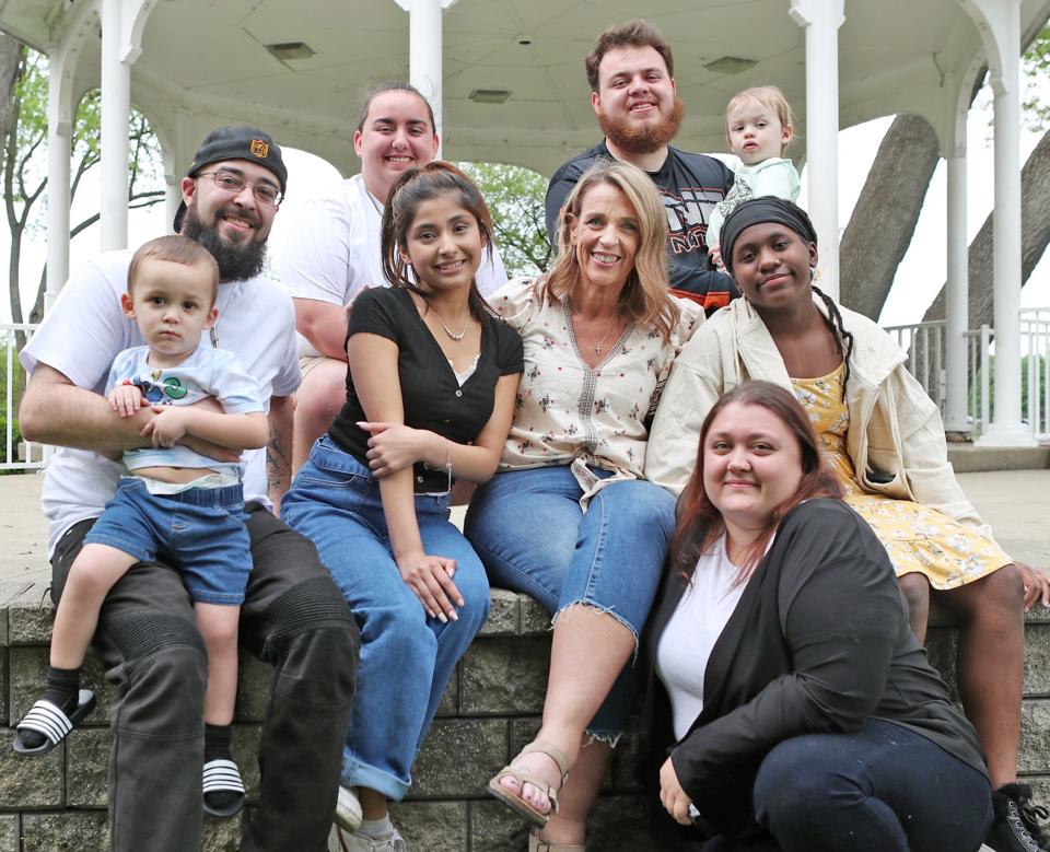 Jennifer Wokojance, center, is surrounded by part of her extended family of foster children and their children along with her adopted and soon-to-be adopted daughters at Lake Anna in Barberton. Back row from left: Allyson Hamrick and her twin brother Aaron, who is holding his son Cole; middle row from left: Cory Copeland holding his son Kaydyn, Miayah, 17, Jennifer Wokojance, Kiyanni Wokojance, 12, and Jeanna Birbrayer, kneeling.