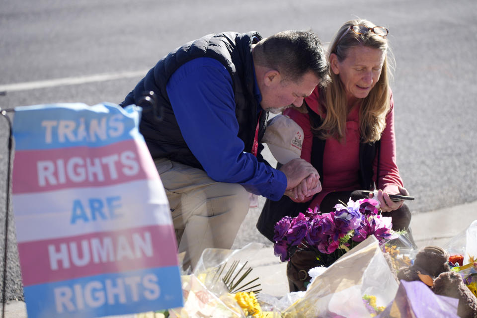 An unidentified man consoles Renee Behr of Colorado Springs, Colo., after she placed a bouquet of flowers on a makeshift tribute near the site of a mass shooting at a gay bar Monday, Nov. 21, 2022, in Colorado Springs, Colo. (AP Photo/David Zalubowski)