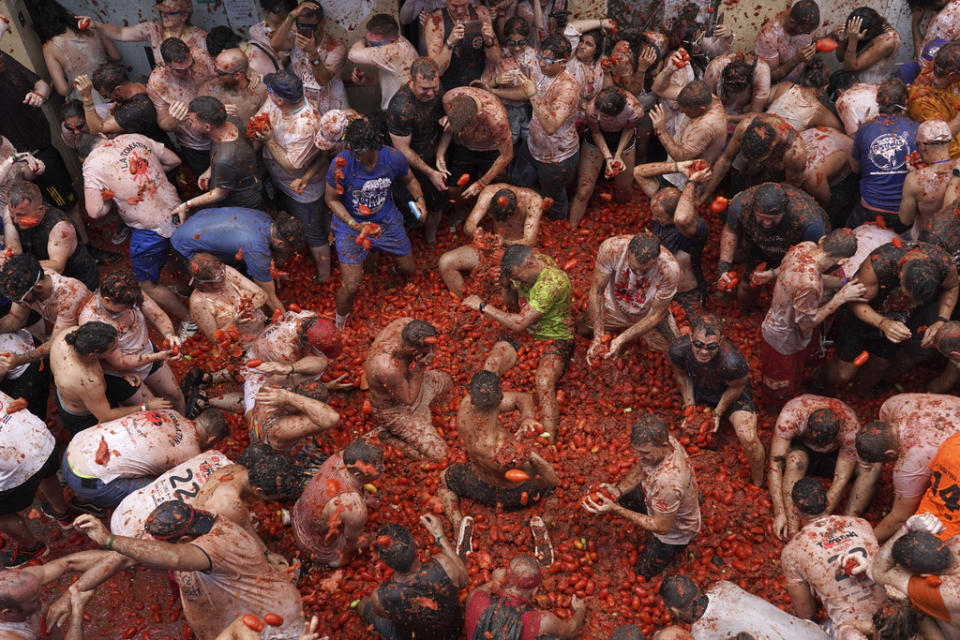 Revellers throw tomatoes at each other during the annual “Tomatina” tomato fight fiesta, in the village of Bunol near Valencia, Spain, Wednesday, Aug. 30, 2023. Thousands gather in this eastern Spanish town for the annual street tomato battle that leaves the streets and participants drenched in red pulp from 120,000 kilos of tomatoes. (AP Photo/Alberto Saiz)