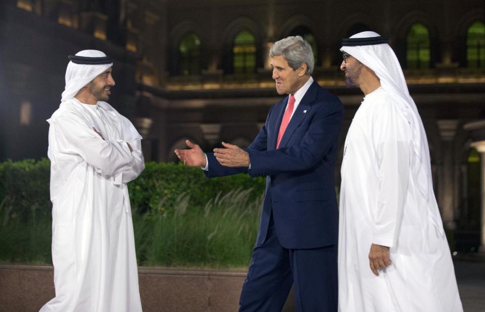 FILE - In this Nov. 10, 2013, file photo, U.S. Secretary of State John Kerry, center, is greeted by United Arab Emirates Foreign Minister Prince Mohammed bin Zayed al Nahyan, right, and Foreign Minister Abdullah bin Zayed Al Nahyan, left, at the Emirates Palace Hotel Abu Dhabi, United Arab Emirates. Kerry has spent nearly half of his first year as secretary of state jumping on and off airplanes and diving headlong into some of the world’s most difficult problems. (AP Photo/Jason Reed, Pool, File)