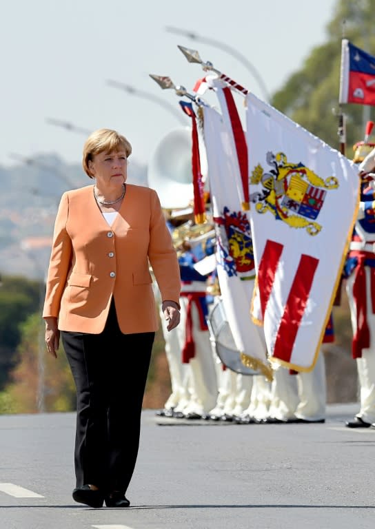 German Chancellor Angela Merkel reviews the honor guard during her welcoming ceremony at Planalto Palace in Brasilia, on August 20, 2015