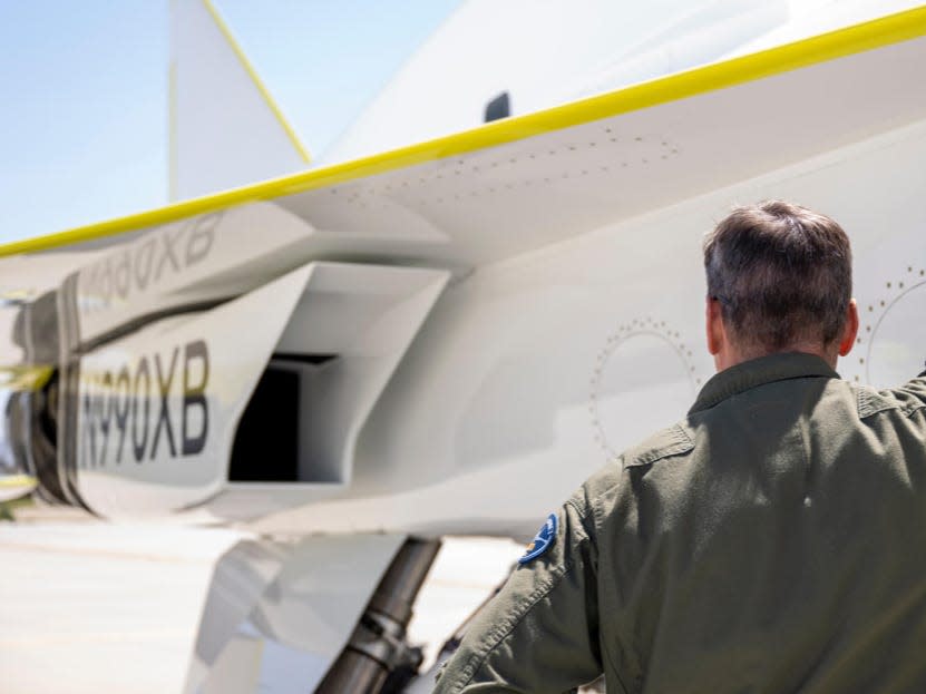 A man in a military uniform standing in front of the XB-1.