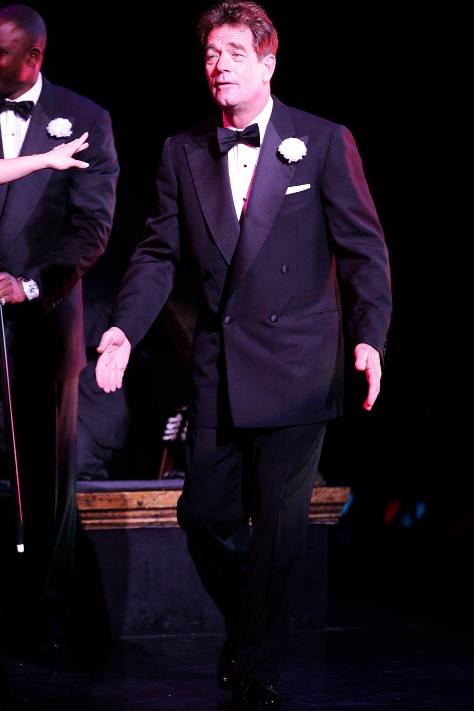 Huey Lewis in a tuxedo on stage