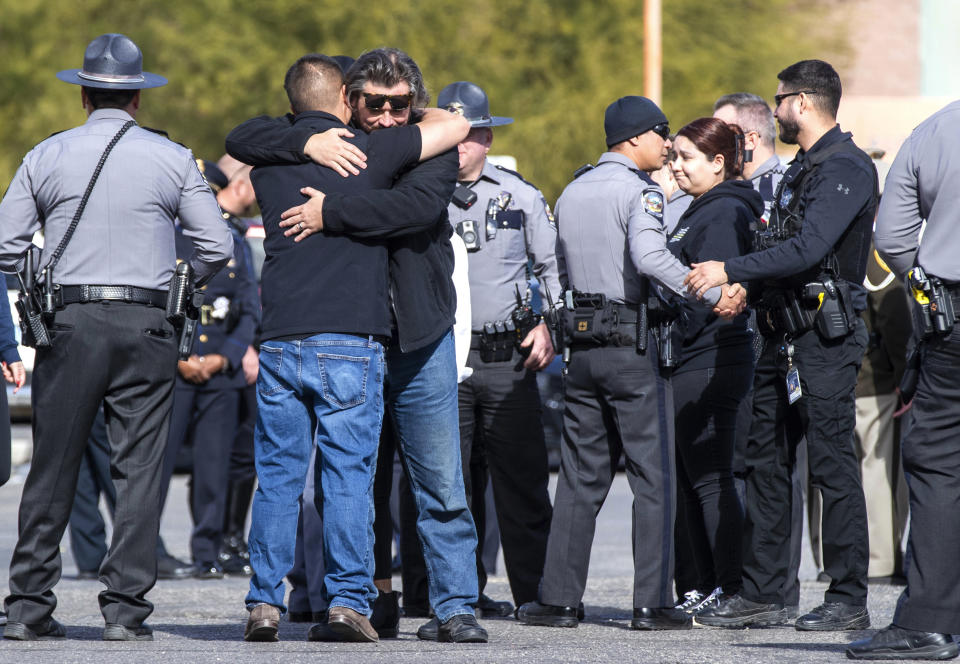 Nevada State Police and other law enforcement officers embrace in the parking lot after the body of a state trooper was taken into the Clark County Coroner's Office in Las Vegas, Thursday, Nov. 30, 2023. Two troopers who were assisting a motorist early Thursday morning were hit by a vehicle and killed, according to Nevada State Police. (Steve Marcus/Las Vegas Sun via AP)