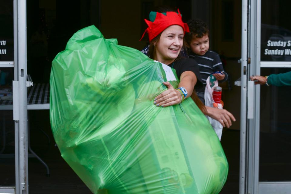 Annabelle Cadd carries a large bag of gifts as she and other volunteers help distribute Christmas items Thursday through the Salvation Army Angel Tree program. Working with Catholic Charities, the Salvation Army will help bring Christmas to local families in need this year.