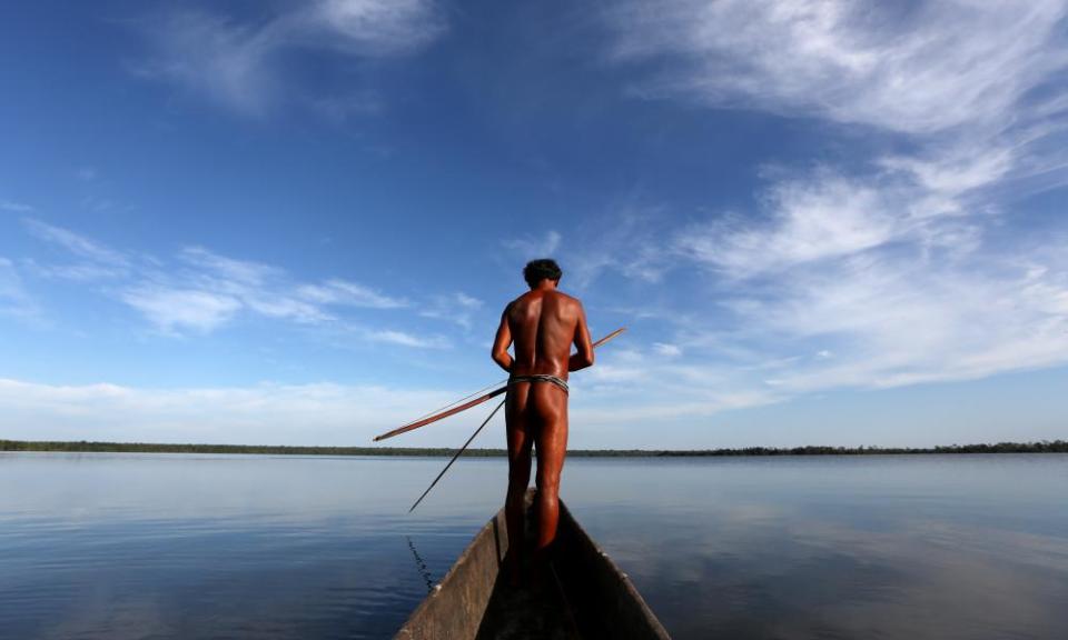 A man fishes with a traditional bow and arrow in a dugout canoe in the Brazilian village of Kamayura. Indigenous groups fear the coronavirus could decimate their communities.