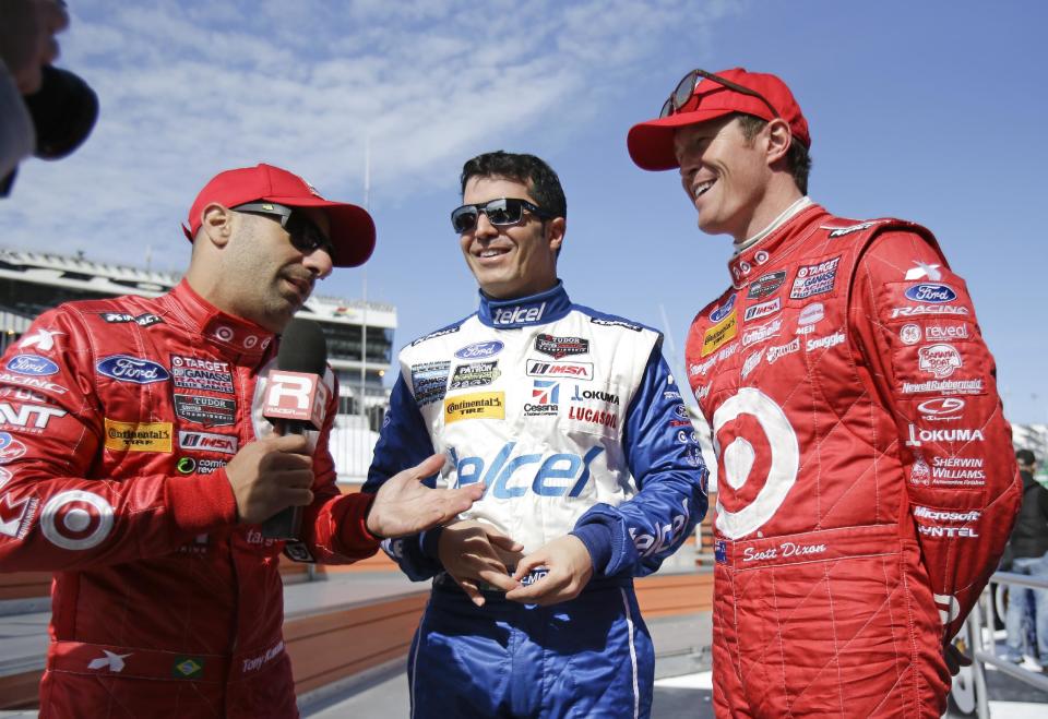 Tony Kanaan, left, of Brazil, interviews Memo Rojas, center, of Mexico, and Scott Dixon, of New Zealand after a practice for the IMSA Series Rolex 24 hour auto race at Daytona International Speedway in Daytona Beach, Fla., Friday, Jan. 24, 2014. (AP Photo/John Raoux)