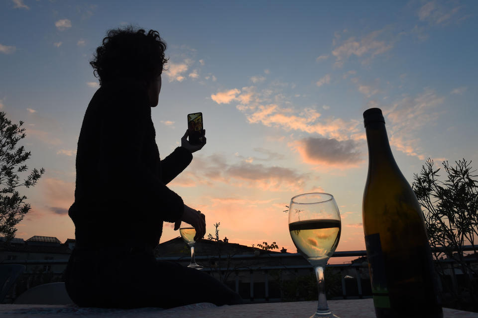 A woman drinks a glass of wine as she speaks and shares a drink with friends via a video call on March 26 in Bordeaux, southwestern France, in the evening on the tenth day of a lockdown aimed at curbing the spread of the COVID-19 in France | Nicolas Tucat—AFP/Getty IMages