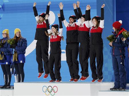 Gold medallists Canada's Jennifer Jones, Kaitlyn Lawes, Jill Officer, Dawn McEwen and Kirsten Wall (3rd L-2nd R) jump on the podium as silver medallists Sweden's Margaretha Sigfridsson and Agnes Knochenhauer (L-2nd L), and bronze medallist Britain's Eve Muirhead (R) look on during the victory ceremony for the women's curling competition at the 2014 Sochi Winter Olympics February 22, 2014. REUTERS/Jim Young