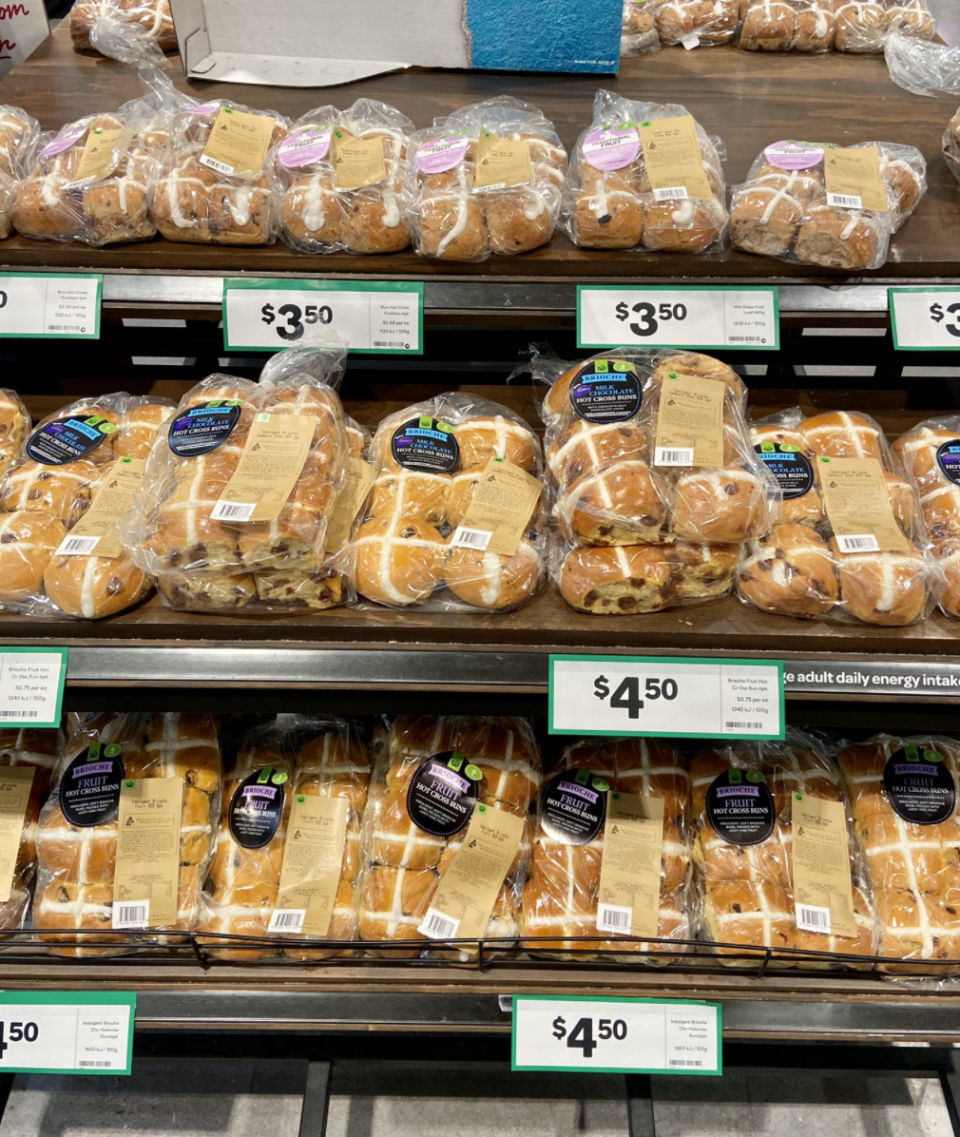 Photo shows hot cross buns on shelves in a Woolworths supermarket.