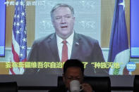 FILE - In this Feb. 1, 2021, file photo, Xu Guixiang, a spokesperson for Xinjiang's Communist Party, drinks as a screen showing a footage of former U.S. Secretary of State Mike Pompeo, during a press conference related to Xinjiang issues at the Ministry of Foreign Affairs office in Beijing. A human rights group appealed to the United Nations on Monday, April 19, 2021 to investigate allegations China's government is committing crimes against humanity in the Xinjiang region. (AP Photo/Andy Wong, File)