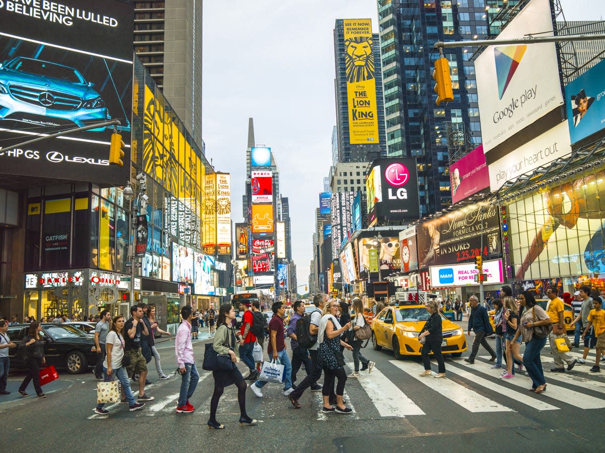 Pedestrians in Times Square NY walking around and shopping.