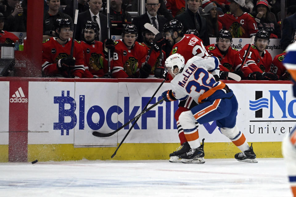 New York Islanders center Kyle MacLean (32) and Chicago Blackhawks defenseman Jaycob Megna (24) chase the puck during the first period of an NHL hockey game Friday, Jan. 19, 2024, in Chicago. (AP Photo/Matt Marton)