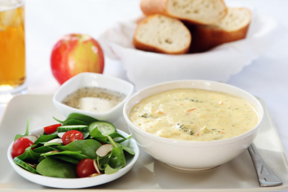 Bowl of soup with side salad, bread, apple, and drink, suggesting a healthy meal for a date