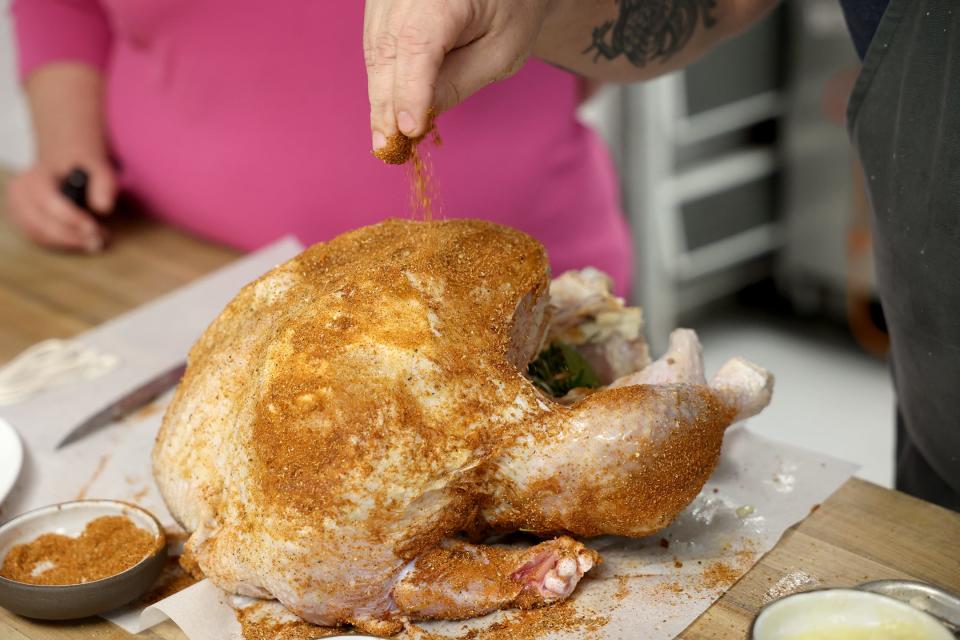 Chef Brandon Carter, executive chef for Farm Group, seasons the turkey with a rib rub as he prepares it for the smoker.