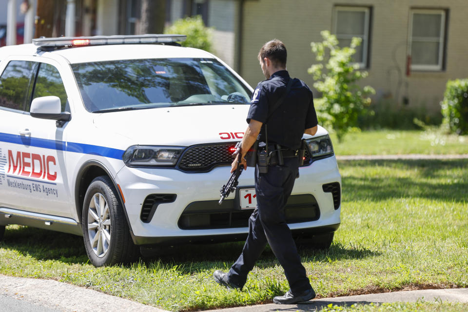 A Charlotte Mecklenburg Police Department officer walks carrying a gun in the neighborhood where a shooting took place in Charlotte, N.C., Monday, April 29, 2024. CMPD says officers from the U.S. Marshals Task Force were carrying out an investigation Monday afternoon in a suburban neighborhood when they came under gunfire. (AP Photo/Nell Redmond)